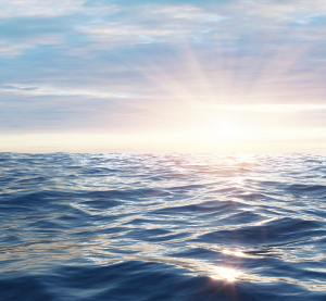 Ruhige Meeresoberfläche im Sonnenuntergang mit weichem Licht und sanften Wellen.