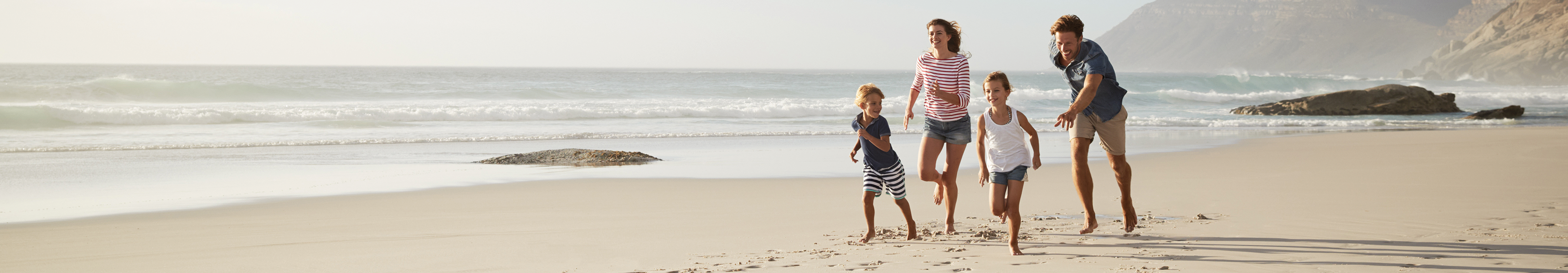 Familie läuft am Sandstrand entlang