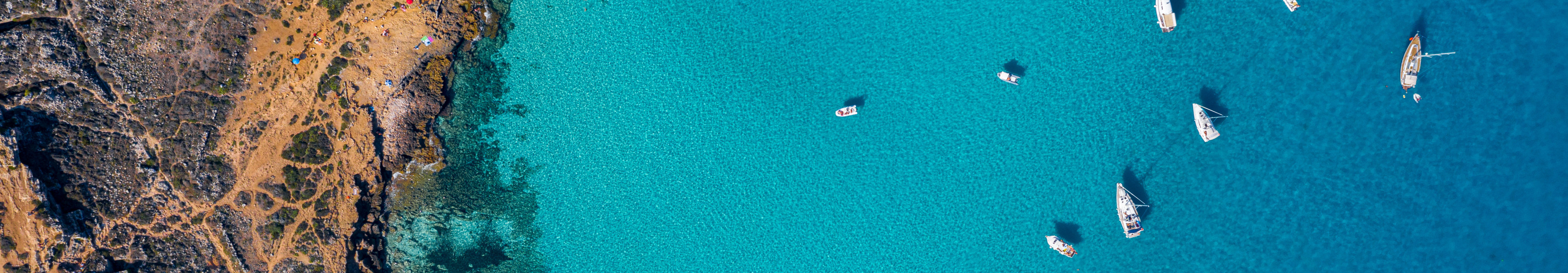 Drohnenaufnahme der Cala Rossa auf Favignana, &Auml;gadische Inseln bei Sizilien, mit t&uuml;rkisblauem Wasser und zahlreichen Booten.