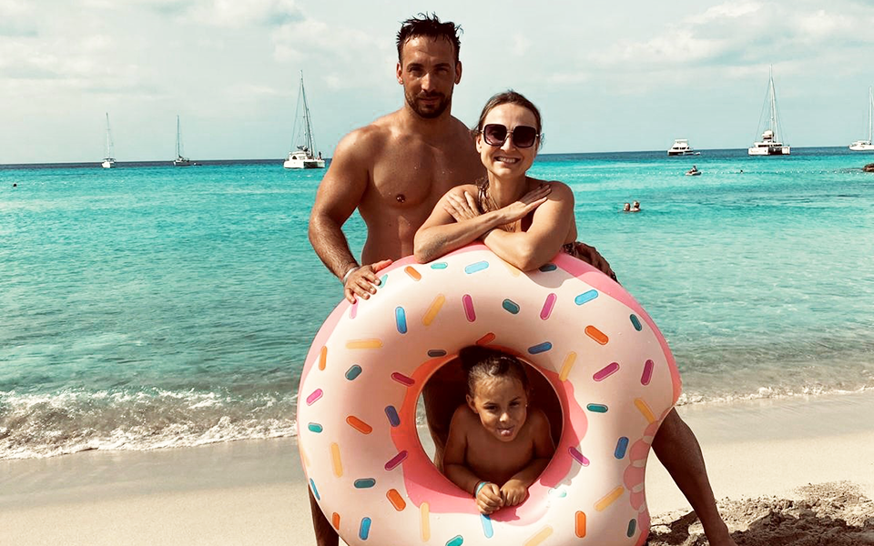 Vater und Mutter mit Tochter am Strand mit Schwimmreifen